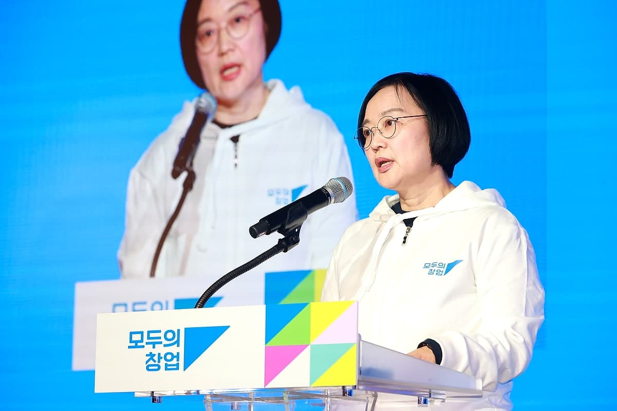 '모두의 창업' 로고가 걸린 연단에서 발표 중인 중소벤처기업부 장관 — 뒤 대형 화면에 같은 장면이 비친다