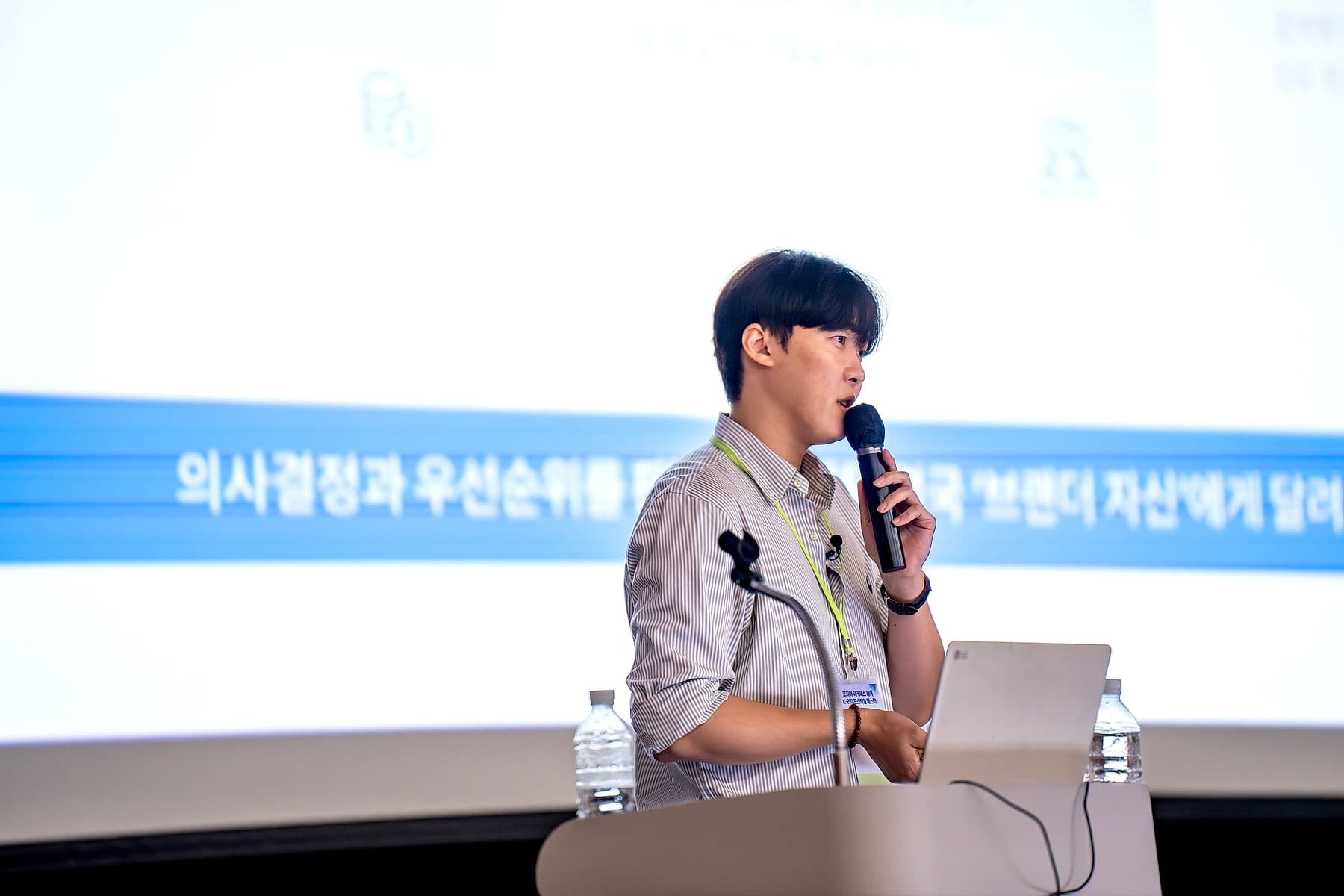 대형 스크린 앞 연단에서 마이크를 들고 강연 중인 송건호